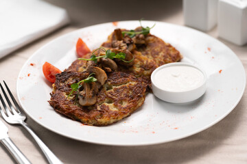 Potato pancakes with mushrooms. Potatoes pancakes on white plate with sour cream. Copy space for text.
