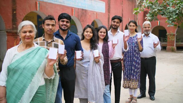 Voters standing in a queue showing their voter identification cards - general elections  state elections  India. Male and female voters of all age waiting for their turn to vote during the election...