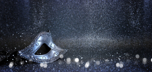 Photo of elegant Venetian mask over glitter silver background