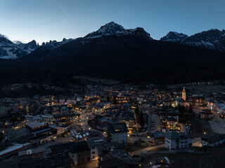Aerial drone view of Andalo town at night with mountains background in winter. Snow covered Italian...