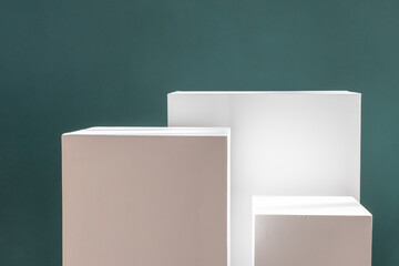 Three white rectangular boxes against a green wall with shadows. Product photography background. Pedestal for cosmetic product and packaging mockups display presentation