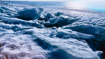 Ice blocks on sunny snowy seaside. Ice drifts on shore of frozen sea. Natural backgrouns with ricy rocks. Snow. March. Winter landscape. North. Soft focus. film grain pixel texture. Defocused.