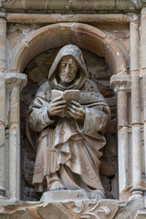 A niche with a sculpture of a Franciscan monk reading a sacred book - obrazy, fototapety, plakaty