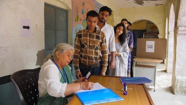 Indian election officer checking the documents and applying the ink on the index finger of a citizen - general elections  democracy  poll. People standing in the queue and waiting for their turn to...