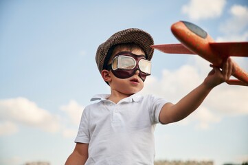 Retro style aviator glasses, with toy plane. Little boy is playing outdoors at daytime