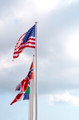 Flags of America, Italy, France of the European Union. National waving flag of united states on pole against blue cloudless sky in daylight
