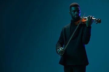 Poster Elegant man in black suit playing the violin on a vibrant blue background with passion and skill © SHOTPRIME STUDIO