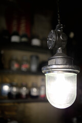 An original lamp on the background of the shelves of the bar counter in an old cafe.