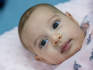 portrait for 3 month 6 kilos baby while lying on his back looking at the camera with no facial...