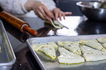 preparing arabic traditional pastries by female hands stuffing them with spinach and red chili