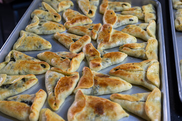 baked stuffed pastries on black marble background ready to be served and moved from aluminum tray to bowls on dinner table or in school kids back bag