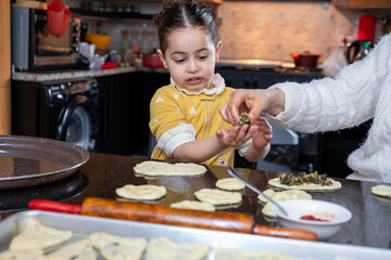 Cheerful kid helping mother in preparing pastries in kitchen , preparing food together
