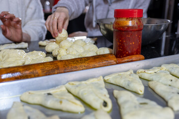 preparing arabic traditional pastries by female hands stuffing them with spinach and red chili