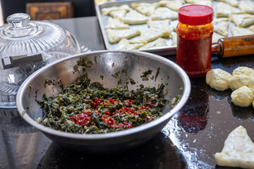 preparing arabic traditional pastries by female hands stuffing them with spinach and red chili