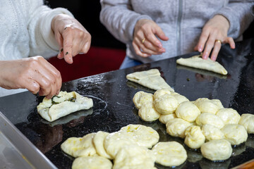 preparing arabic traditional pastries by female hands stuffing them with spinach and red chili