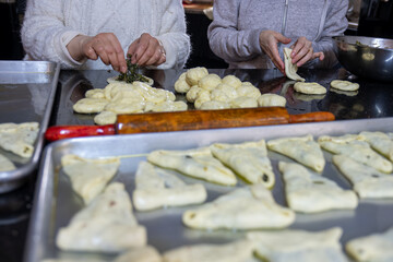 preparing arabic traditional pastries by female hands stuffing them with spinach and red chili