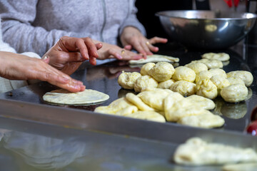 preparing arabic traditional pastries by female hands stuffing them with spinach and red chili