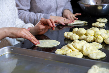 preparing arabic traditional pastries by female hands stuffing them with spinach and red chili