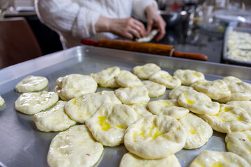 old woman hands using rolling pin to flatten the dough  on black marble  covered with oil
