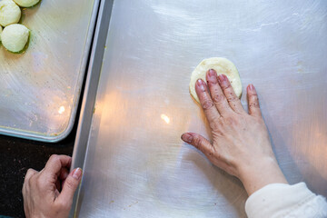 Female hands flattening dough balls and shaping it in circles to be stuffed later, dough hand made