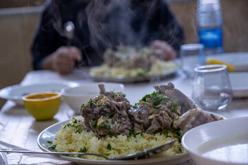 hot fresh mansaf steam with hands around it ready to be eaten on family table for iftar