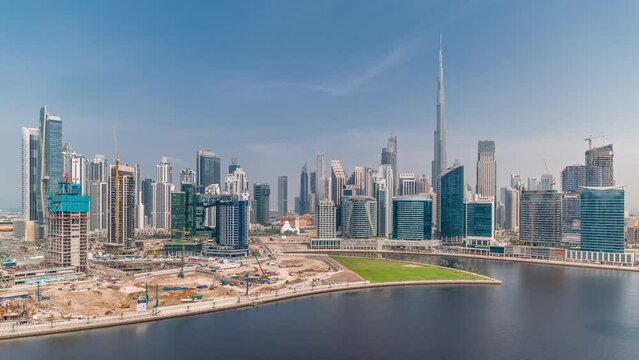 Aerial panoramic view to Dubai Business Bay and Downtown with the various skyscrapers and towers along waterfront on canal timelapse. Construction site with cranes