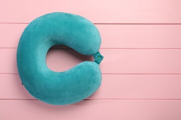 Turquoise travel pillow on pink wooden table, top view. Space for text