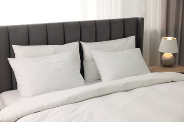 Soft white pillows and duvet on bed at home