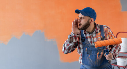 Painter man holding a paint roller standing in room shouting with mouth wide open to the side. Wall with orange spot. Banner.