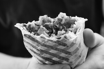 Niezdrowe rakotwórcze jedzenie, tłusty kebab fast food w dłoni czarno-białe zdjecie