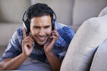 Man, headphones and listening to song on couch, relax and streaming radio for music or sound. Happy...