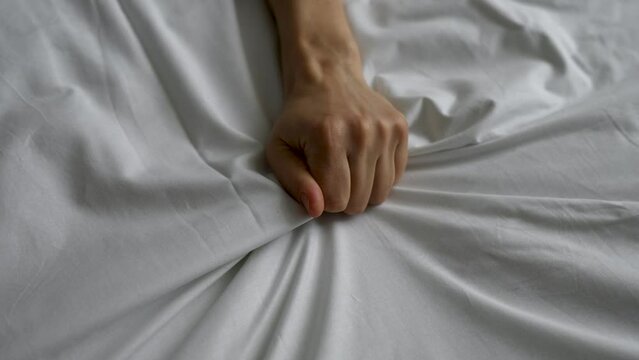 Passion woman squeezed the bed sheet with her hand