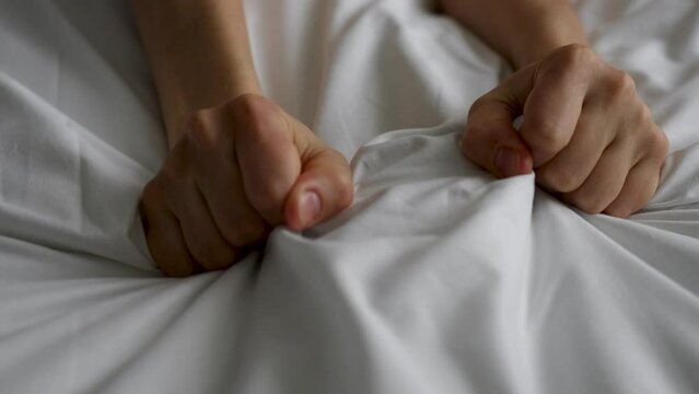 Passion woman squeezed the bed sheet with her hand