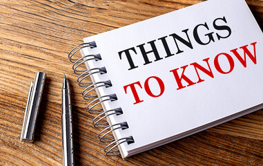 THINGS TO KNOW text on notebook with pen on wooden background