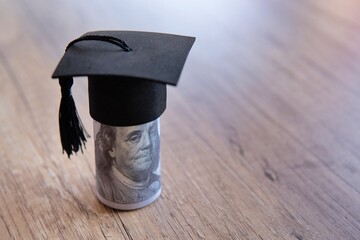 Closeup image of graduation cap and money on table. Scholarship, educational fees concept. Copy...