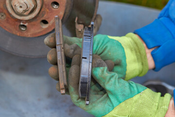 new and old brake pads in hand, auto mechanic shows brake pads in his hands, compares new and old car brake pads © retbool