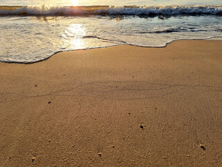 The perspective of the sea waves hitting the sand of the beach reflection with the sun