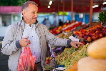 Man choosing grape in fruit shop