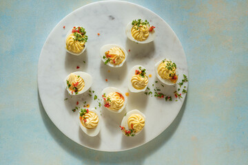 Deviled eggs with spicy oil on ligh blue background with sunligh and harsh shadows, directly above - 752296931