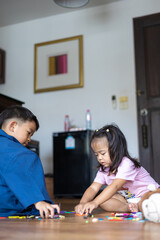 Fototapeta premium Asian sister and brother play together in cozy room wooden house floor