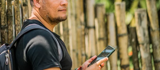 Fotobehang plano medio de hombre al aire libre con su celular en la mano  © ASTRO