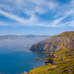 Fototapeta premium calm sea bay with rocky coast under blue sky, summer sea vacation scene