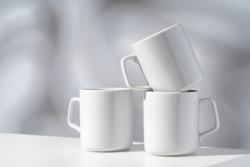 White ceramic mugs on gray background with shadows