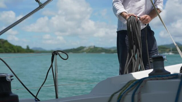 Close Up of Sailman Hands Unwinding Rope From Winch of Sailboat on Sunny