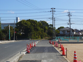 Fototapeta na wymiar 作業が終了した道路工事。ランドスケープ画像。 日本の建築現場の風景。 工事箇所に注意を促すパイロンの列。