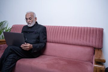 Fototapeta premium Portrait of mature Indian or Latin business man ceo trader using laptop computer, typing, working from home