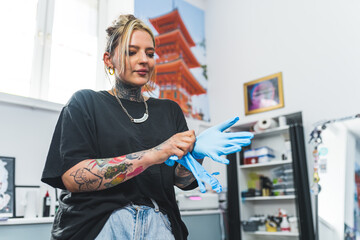 Female tattoo artist getting ready for a tattoo session with her new client. Safety first. Girl...