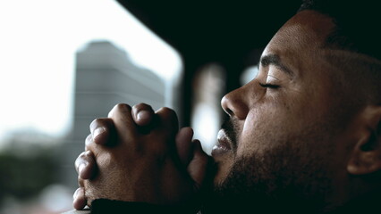 One faithful young hispanic black man in PRAYER gazing at SKY from balcony in deep mental contemplation. Profile close-up face of a SPIRITUAL South American 20s person