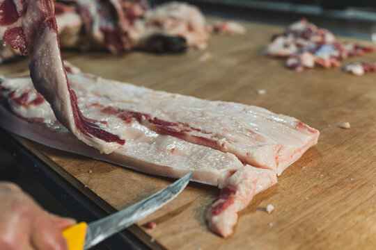 a butcher cutting thin pig meat slices at the slaughterhouse. High quality photo