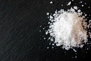 Obraz na płótnie Canvas White salt cristals for food on the black background.